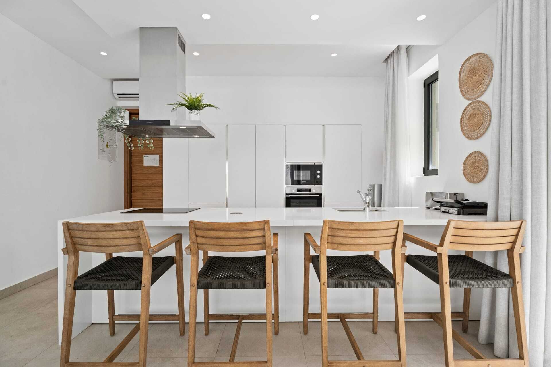 A modern kitchen with white cabinetry, a central island with bar stools, and a built-in oven.