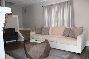 A living room with a sofa, a coffee table, a chair, and a staircase. - 3-bedroom house in phenomenal Columbus with cool AC breeze (Columbus)