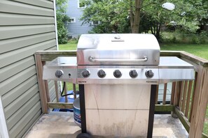 A stainless steel Char-Broil gas grill with four burners and a side burner, mounted on a wooden deck. - 3-bedroom house in phenomenal Columbus with cool AC breeze (Columbus)
