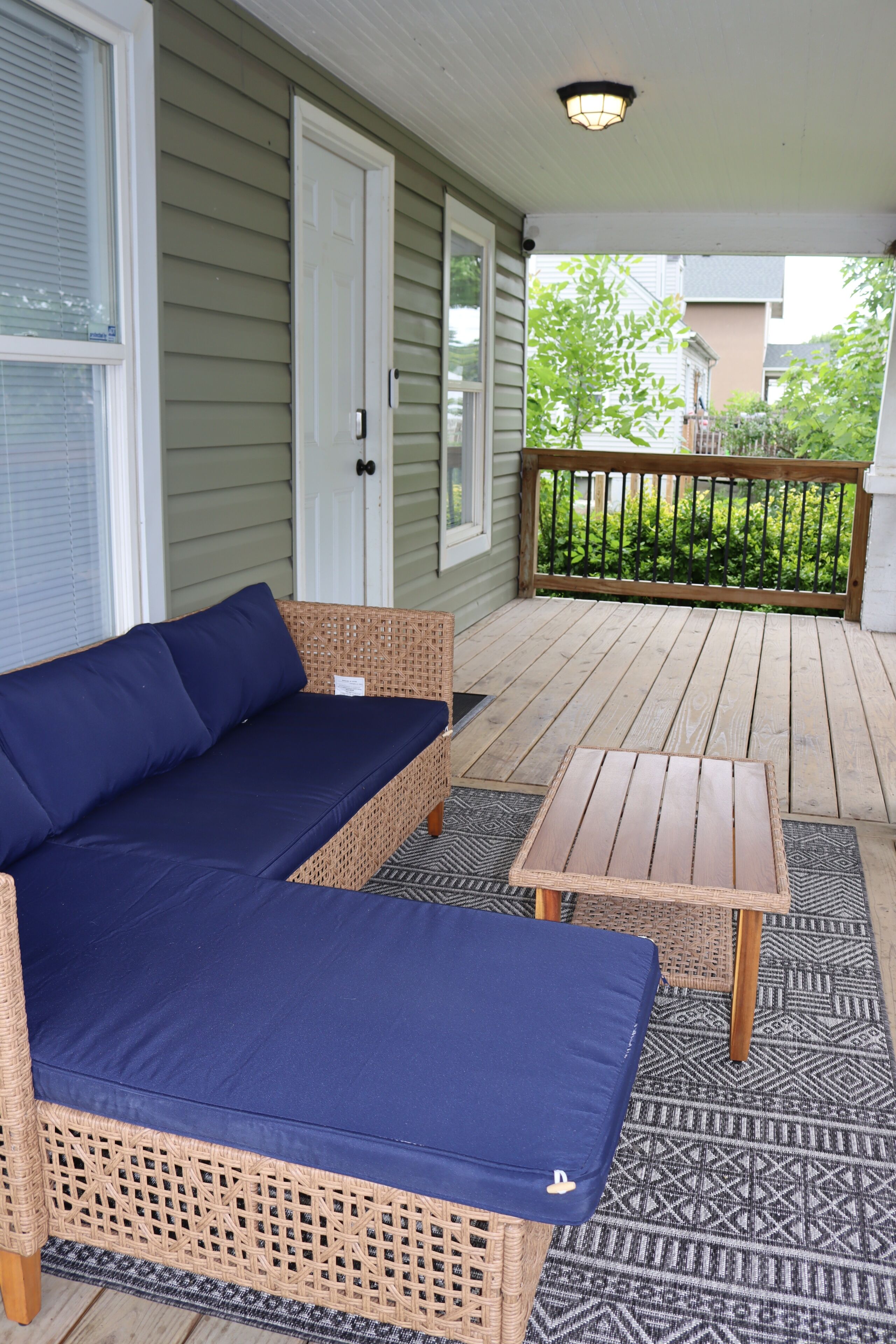 A covered porch with a wicker sofa and a small table.
