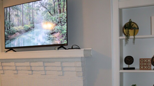 Uma sala de estar com lareira, uma TV de tela plana acima e uma estante à direita.