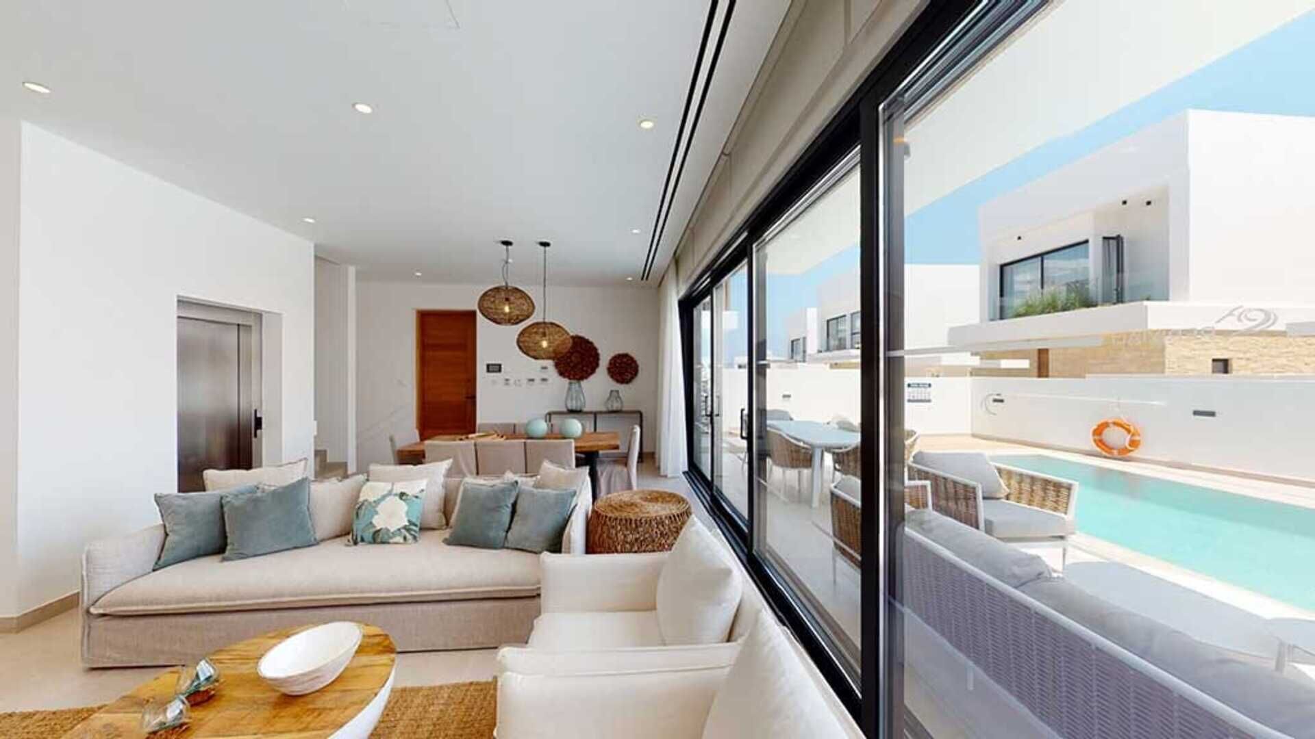 A modern living room with a sofa, dining table, and a view of a pool.