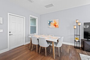 A dining area with a white table, grey chairs, and a wooden floor. - 7 Minutes to Campus! (Gainesville)