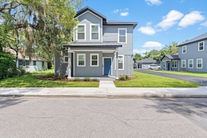 A two-story residential building with a front porch, a garage, and a well-maintained lawn. - 7 Minutes to Campus! (Gainesville)