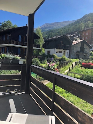 A balcony with a view of a village, including buildings and a mountain in the distance. - Luxury Alpine Retreat|Zermatt 1068 (Wallis)