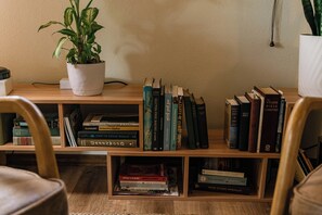 A bookshelf with various books, a potted plant, and a wooden floor. - Whispering Pines Sanctuary near Payette River & Hot Springs (Garden Valley)