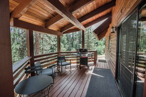 A wooden deck with a grill and seating area, overlooking a forested area. - Whispering Pines Sanctuary near Payette River & Hot Springs (Garden Valley)