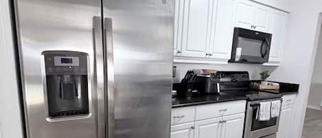 Une cuisine moderne dotée d’appareils électroménagers en acier inoxydable, de meubles blancs et d’un plancher en bois.