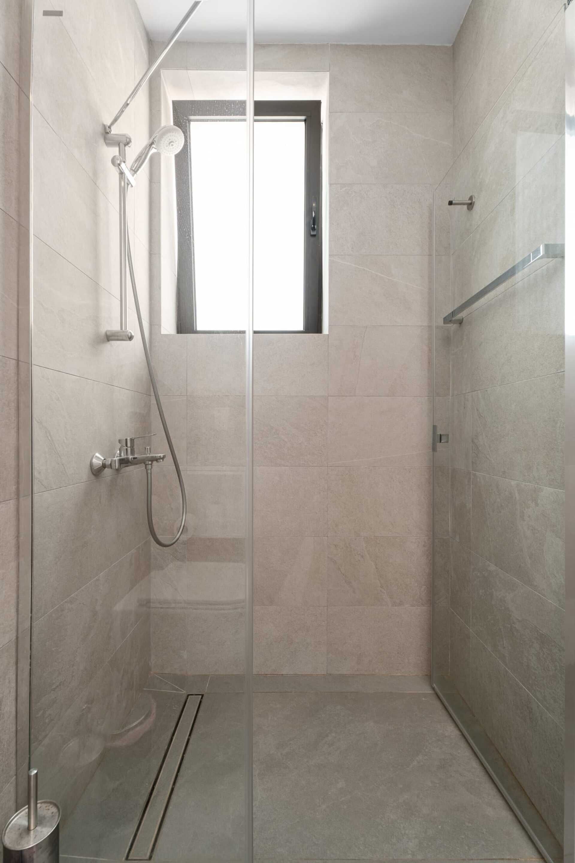 A modern shower with a glass door, a handheld showerhead, and a handheld shower attachment.
