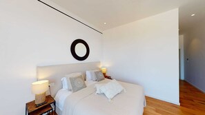 Un dormitori modern amb un llit gran, abacaments, una decoració circular a la paret i un terra de fusta.
