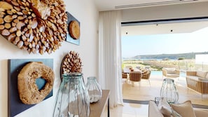 A modern interior with a view of the sea, featuring a dining area with wicker furniture and a table with glass vases. - Secluded Seaside Bliss | Villa 1039 (Famagusta)