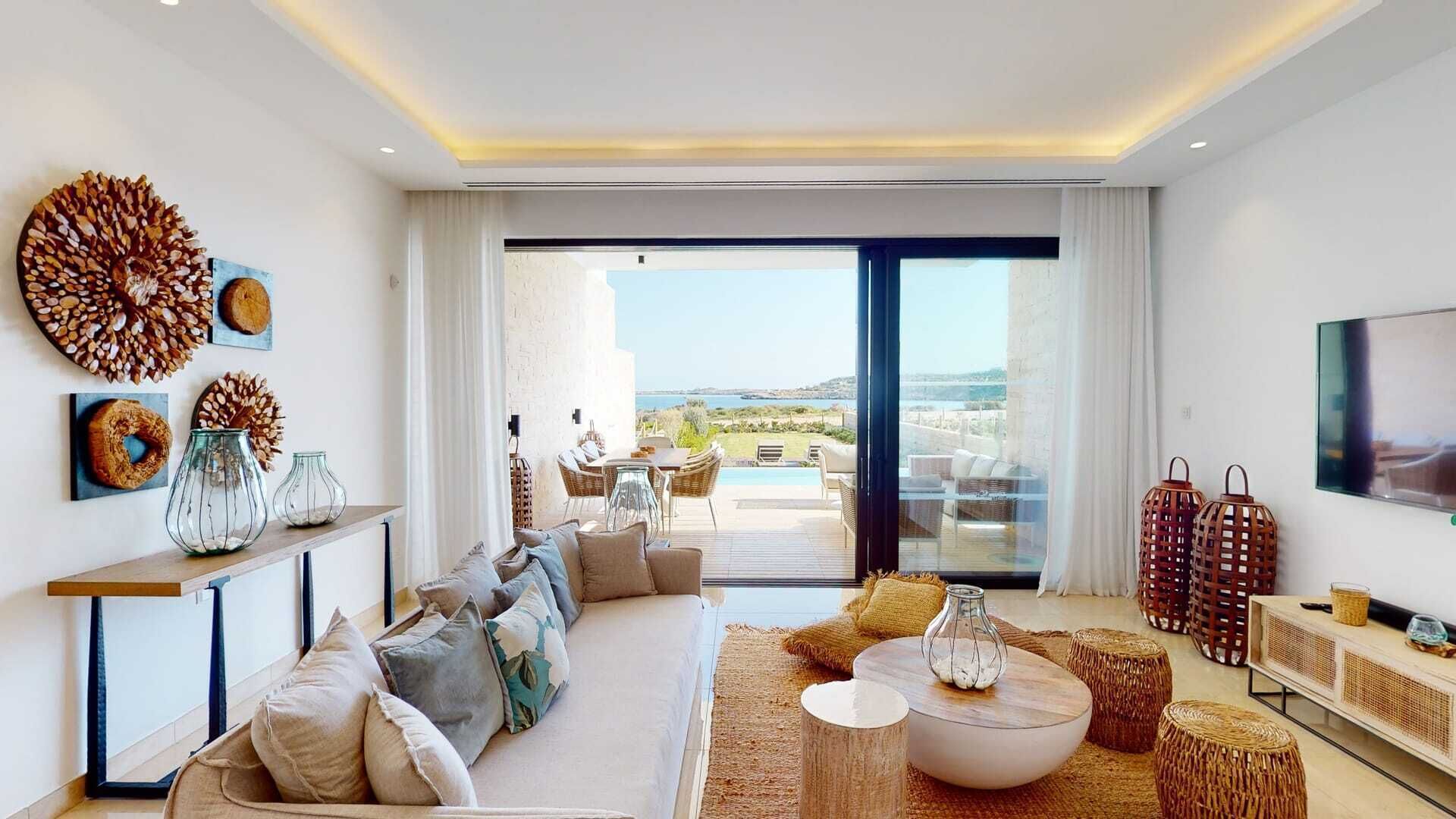 A modern living room with a sofa, coffee table, and decorative items. There is a large window with a view of the outdoors.