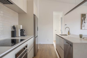 Eine moderne Küche mit Einbauofen, Kaffeemaschine und Geschirrspüler.