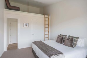 A bedroom with a bed, pillows, a blanket, a ladder, and a door. - The Lookout, BBQ, Free Parking, AC, Heating (Lake Hayes Estate)