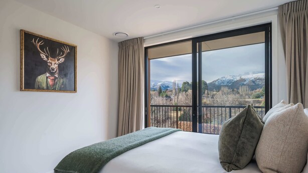 Ein Hotelzimmer mit einem großen Bett, Blick auf Berge und einem Hirschgemälde an der Wand.