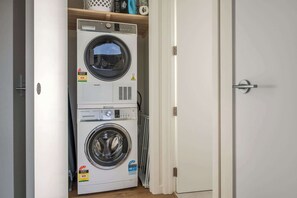A laundry room with two stacked washing machines and a dryer. - The Lookout, BBQ, Free Parking, AC, Heating (Lake Hayes Estate)
