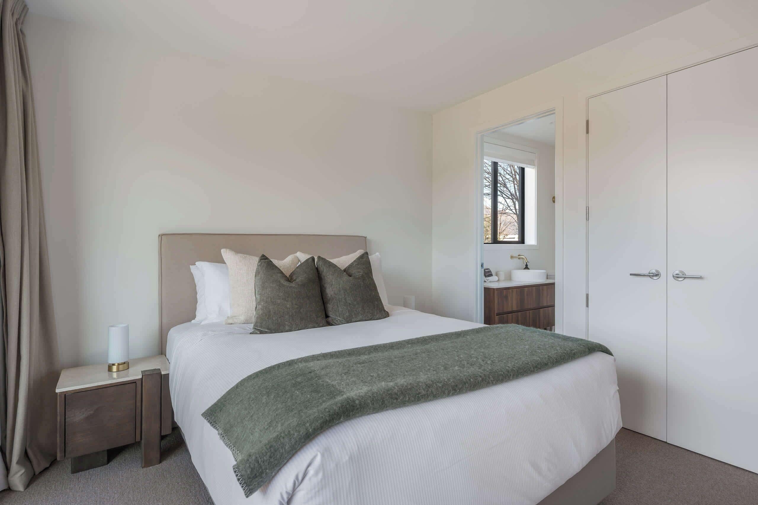 A bedroom with a bed, a nightstand, a mirror, and a door.