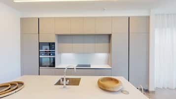 A modern kitchen with a central island, built-in oven, and a large window.