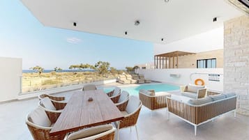 En takterrass med pool, utemöbler och utsikt över stranden.