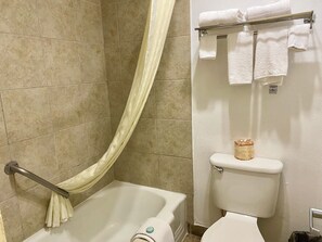 A bathroom with a bathtub, toilet, and a towel rack with folded towels. - Super 8 Downtown_1 King Bed (Albuquerque)