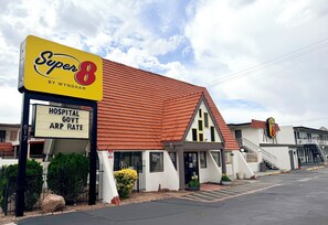 A Super 8 motel with a red roof, a sign indicating hospital, government, and ARP rates, and a parking lot. - Super 8 Downtown_1 King Bed (Albuquerque)