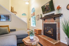 A living room with a fireplace, a sofa, a coffee table, and a staircase. - Updated Mt Baker Retreat w/ Private Hot Tub + Pool (Deming)