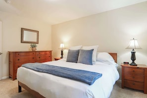 Ein Schlafzimmer mit einem Bett, zwei Nachttischen, einer Kommode, einem Spiegel und einer Wanduhr.