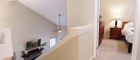A hallway with a staircase leading to a bedroom.