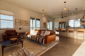 A spacious living area with a sofa, a coffee table, and a dining area with chairs. - Park-edge hot tub retreat · dogs welcome (Joshua Tree)