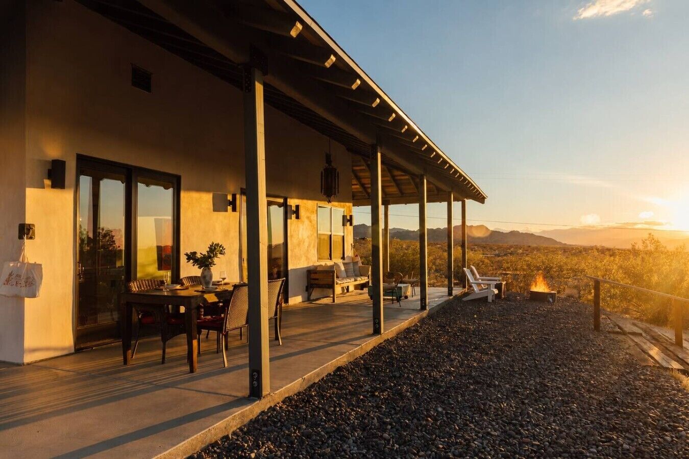 Une terrasse extérieure moderne comprenant un espace repas, des sièges et un foyer.