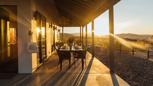 Un patio al aire libre con una mesa y sillas, una planta en maceta y vistas del paisaje.