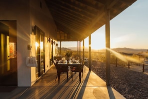 Un patio al aire libre con una mesa y sillas, una planta en maceta y vistas del paisaje.