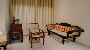 A room with a sofa, a wooden chair, a small table, and a cabinet.