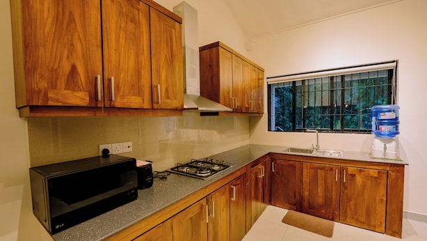 A kitchen with wooden cabinets, a gas stove, a microwave, and a water dispenser.