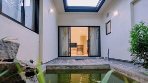 A modern interior with a glass door leading to a seating area, a small water feature, and a stone wall.