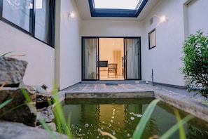 A modern interior with a glass door leading to a seating area, a small water feature, and a stone wall.