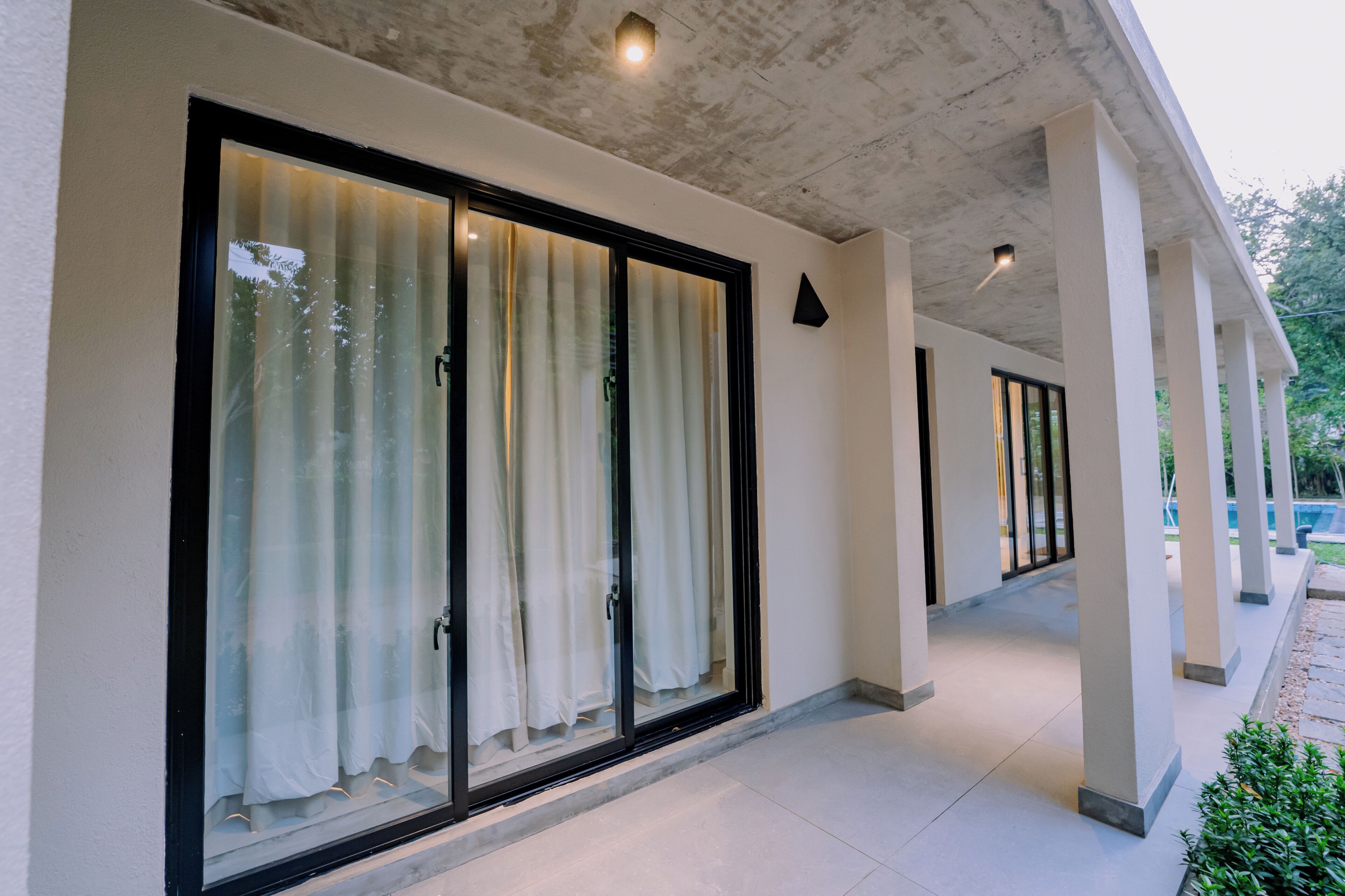 A corridor with large sliding glass doors, a concrete ceiling, and a tiled floor.