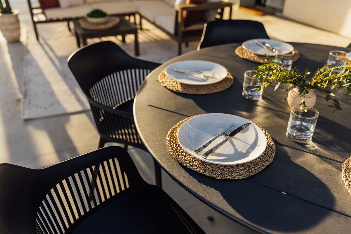 An outdoor dining area with round tables, black chairs, and woven placemats.