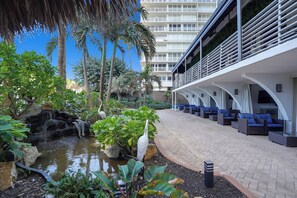 A hotel courtyard with a water feature, palm trees, and outdoor seating. - Lovely Beachfront Condo w/Balcony overlooking the Atlantic Ocean (Fort Lauderdale)