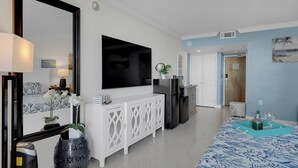 Ein modernes Wohnzimmer mit Flachbildfernseher, einer weißen Ablage und einem gemusterten Teppich.