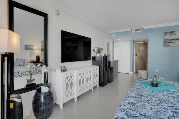 Una sala de estar moderna con un televisor de pantalla plana, un mueble bajo blanco y un tapete estampado.