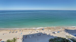 Une plage avec un ciel dégagé, une eau calme et un rivage sablonneux agrémenté de transats et de parasols.