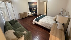 A bedroom with a bed, a dresser, a nightstand, a lamp, and a window with blinds. - Little Valley Oasis Resort Pool & Palm Paradise (St. George)