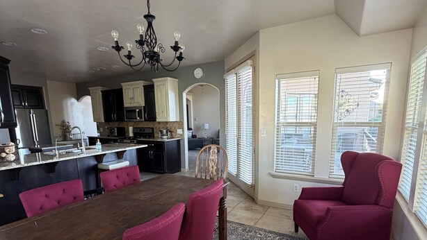 A spacious kitchen with modern appliances, a dining area with a large wooden table and red chairs, and a living room with a red armchair. - Little Valley Oasis Resort Pool & Palm Paradise (St. George)