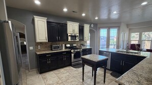 A modern kitchen with dark cabinetry, stainless steel appliances, and a granite countertop. - Little Valley Oasis Resort Pool & Palm Paradise (St. George)