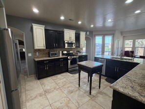 A modern kitchen with dark cabinetry, stainless steel appliances, and a granite countertop.