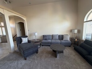 A living room with a grey sofa set, two side tables with lamps, a coffee table, and a carpeted floor.