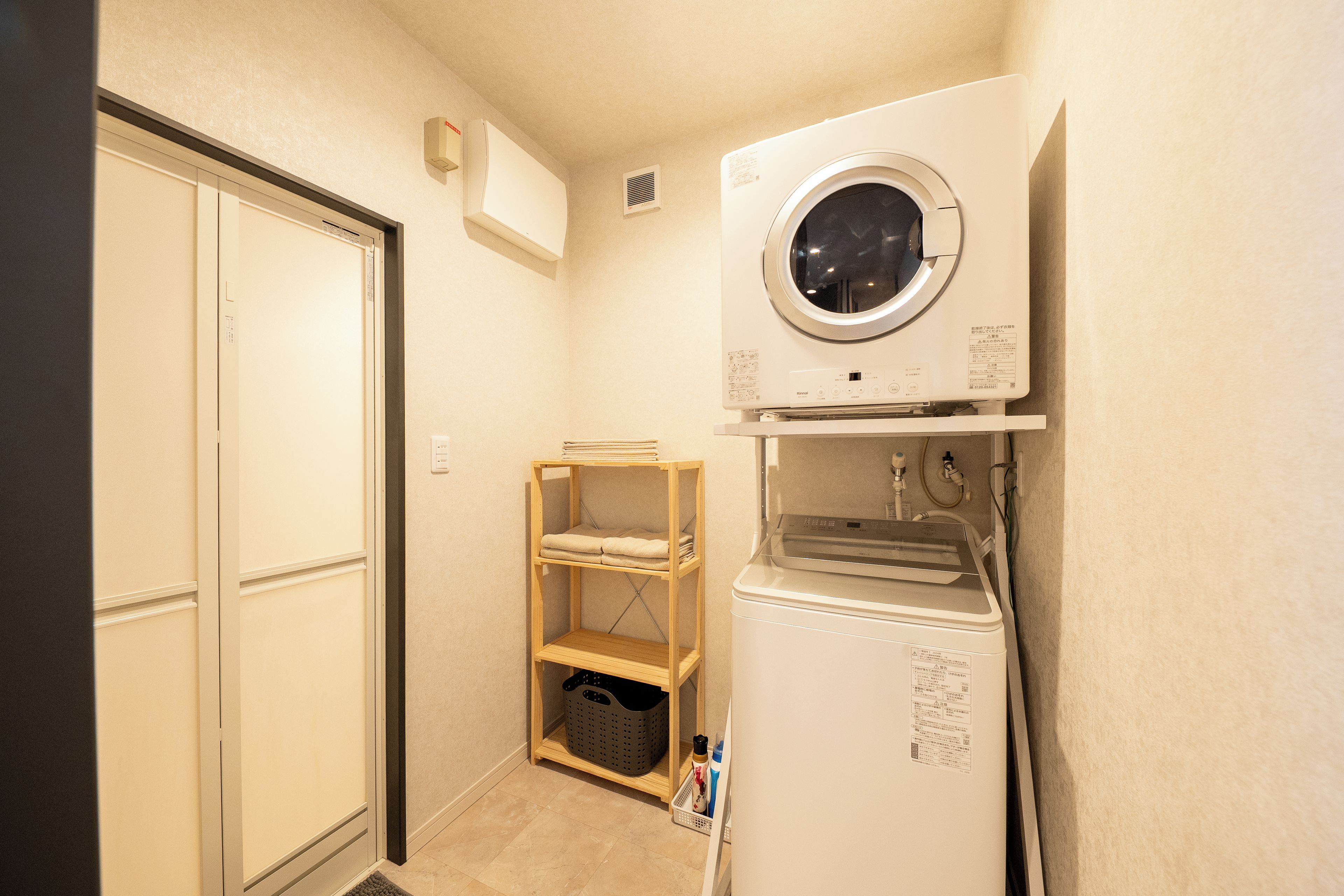 A laundry room with a washing machine, a dryer, and a shelf with folded towels.