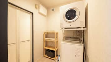 Un cuarto de lavandería con lavadora, secadora y un estante con toallas dobladas.