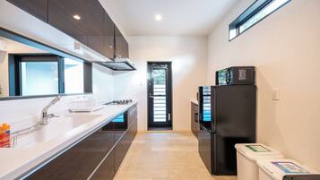A modern kitchen with a stainless steel sink, a black refrigerator, and a microwave on top.
